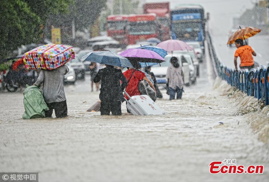 People make their way with their luggage along a flooded road after a rainstorm in Quanzhou City, East China’s Fujian Province, Aug. 29, 2018. (Photo/VCG)