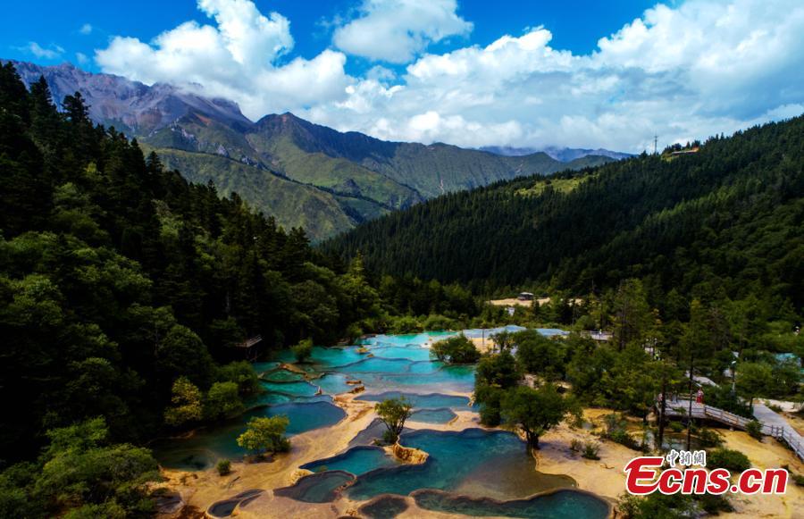 An aerial view of the Huanglong scenic area in Sichuan Province. A UNESCO World Heritage site, the area is known for its colorful pools formed by calcite deposits, especially in Huanglonggou (Yellow Dragon Gully), as well as diverse forest ecosystems, snow-capped peaks, waterfalls and hot springs. The Wucai Pond (Five-Colored Pond) is one of its top attractions. (Photo: China News Service/Yang Jian)