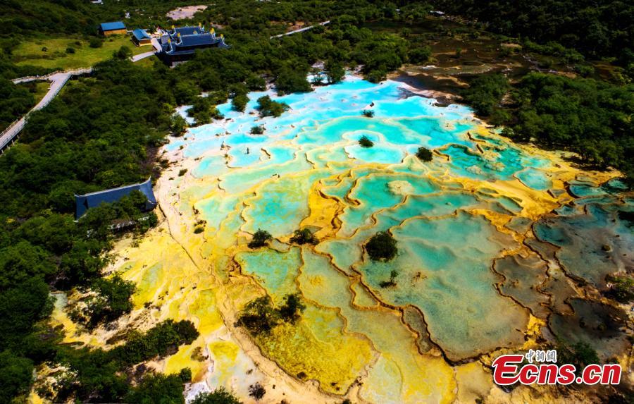 An aerial view of the Huanglong scenic area in Sichuan Province. A UNESCO World Heritage site, the area is known for its colorful pools formed by calcite deposits, especially in Huanglonggou (Yellow Dragon Gully), as well as diverse forest ecosystems, snow-capped peaks, waterfalls and hot springs. The Wucai Pond (Five-Colored Pond) is one of its top attractions. (Photo: China News Service/Yang Jian)