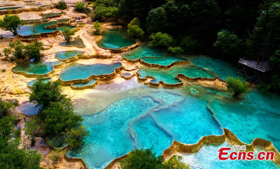 An aerial view of the Huanglong scenic area in Sichuan Province. A UNESCO World Heritage site, the area is known for its colorful pools formed by calcite deposits, especially in Huanglonggou (Yellow Dragon Gully), as well as diverse forest ecosystems, snow-capped peaks, waterfalls and hot springs. The Wucai Pond (Five-Colored Pond) is one of its top attractions. (Photo: China News Service/Yang Jian)