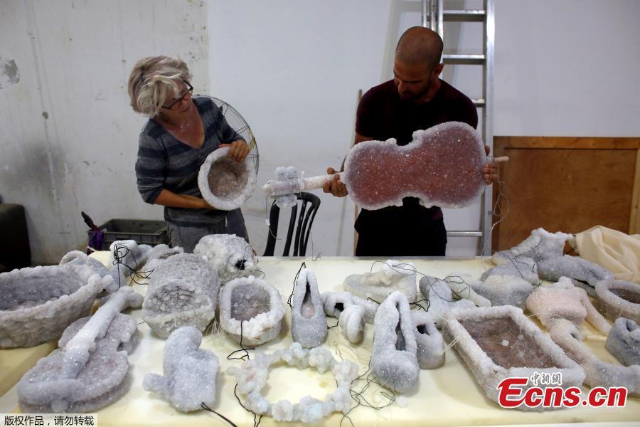 Israeli artist Sigalit Landau (L) and her partner Yotam, look at some of her art pieces, objects covered in salt crystal formations after they were removed from the hyper-saline waters of the Dead Sea, at Landau\'s studio in Kibbutz Almog, Israel, Aug. 30, 2018. (Photo/Agencies)