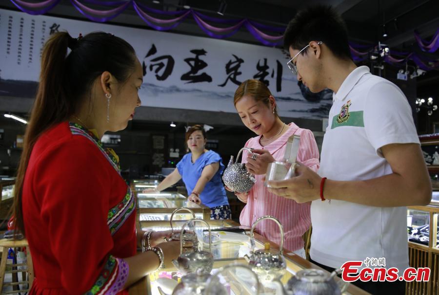 People visit Yang Changgan\'s studio in Zhangjiajie City, Central China’s Hunan Province, Sept. 5, 2018. Yang, born in 1986 in Guizhou Province, was exposed to the craft of silverwork from an early age. After completing his bachelor’s degree at Nanchang Institute of Technology in 2010, he learned with Yang Guangbin, a master crafter of the silver ornaments of the Miao people. He then opened his own studio in Zhangjiajie in 2015, mainly developing silver pot products. Yang said it takes 10-15 days to make a silver pot as the process involves nearly 100 steps, including pounding, refining and wielding. Yang said his creations sell well in nearly 20 countries and regions. (Photo: China News Service/Wu Yongbing)