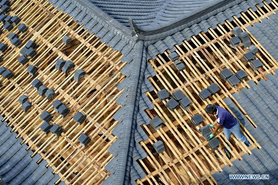 A worker lays tiles on the rooftop in the construction site of a Dong ethnic group relocation compound in Yejiaoyuan Village of Xuan\'en County, central China\'s Hubei Province, Sept. 8, 2018. The residence compound, a relocation project aimed at aiding the 40 local families that live under the poverty line, is designed to boost the local tourism as the buildings feature the Dong ethnic group originality that may attract tourists for a culture experience. (Xinhua/Song Wen)