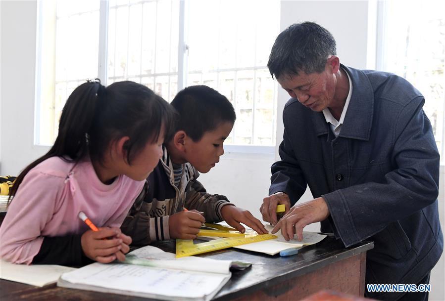 Wang Zhengxiang (1st R) teaches students at Ayiyang Primary School in Sanmeng Village of Luquan Yi and Miao Autonomous County, southwest China\'s Yunnan Province, Sept. 5, 2018. One teacher, eight students, none was and will be given up thanks to rural teacher Wang Zhengxiang. Wang of Miao ethnic group, 56, is the only teacher and has been teaching at the remote village primary school of Ayiyang for 38 years. Ayiyang Primary School, lying at an altitude of 2,600 meters above sea level and surrounded by mountains, is not within easy reach of outside world. There are just eight students at the school. Yet Wang takes care of his students with love, consideration and strong sense of responsibility. He buys shoes and daily goods for poverty-stricken students with his own money, and he has tried every means to keep those who wanted to drop out due to economic insufficiency. \