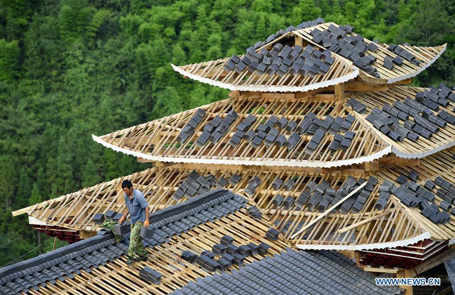 A worker walks on the rooftop of a building in the construction site of a Dong ethnic group relocation compound in Yejiaoyuan Village of Xuan\'en County, central China\'s Hubei Province, Sept. 8, 2018. The residence compound, a relocation project aimed at aiding the 40 local families that live under the poverty line, is designed to boost the local tourism as the buildings feature the Dong ethnic group originality that may attract tourists for a culture experience. (Xinhua/Song Wen)