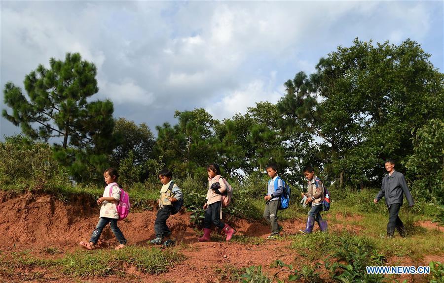 Wang Zhengxiang (1st R) sends students back home after school in Sanmeng Village of Luquan Yi and Miao Autonomous County, southwest China\'s Yunnan Province, Sept. 5, 2018. One teacher, eight students, none was and will be given up thanks to rural teacher Wang Zhengxiang. Wang Zhengxiang of Miao ethnic group, 56, is the only teacher and has been teaching at the remote village primary school of Ayiyang for 38 years. Ayiyang Primary School, lying at an altitude of 2,600 meters above sea level and surrounded by mountains, is not within easy reach of outside world. There are just eight students at the school. Yet Wang takes care of his students with love, consideration and strong sense of responsibility. He buys shoes and daily goods for poverty-stricken students with his own money, and he has tried every means to keep those who wanted to drop out due to economic insufficiency. \