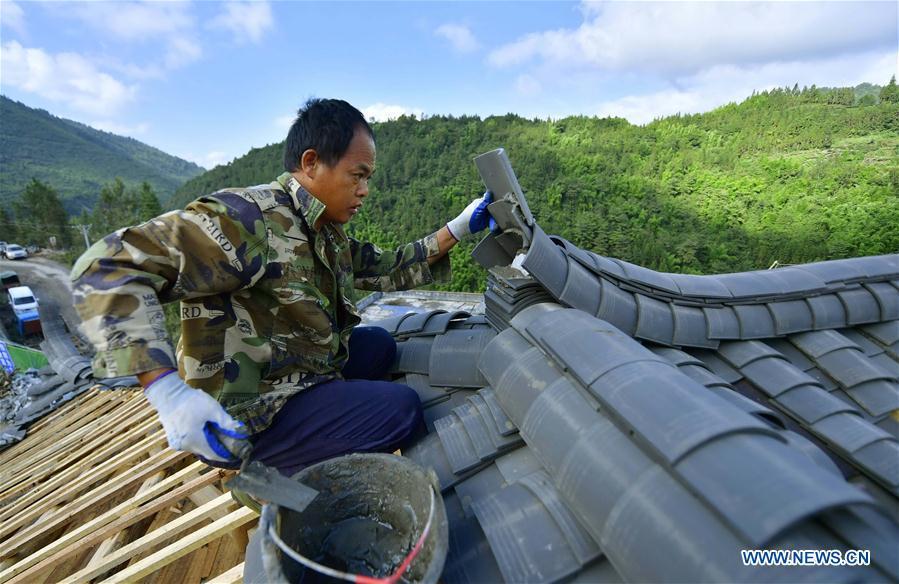 A worker lays tiles on the rooftop in the construction site of a Dong ethnic group relocation compound in Yejiaoyuan Village of Xuan\'en County, central China\'s Hubei Province, Sept. 8, 2018. The residence compound, a relocation project aimed at aiding the 40 local families that live under the poverty line, is designed to boost the local tourism as the buildings feature the Dong ethnic group originality that may attract tourists for a culture experience. (Xinhua/Song Wen)