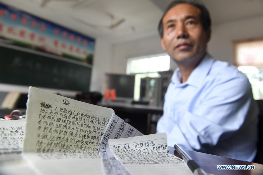 Guo Yue presents the parting words from his former graduated students in Guozhai Primary School, Taihe County of east China\'s Anhui Province, Sept. 7, 2018. Guo, suffering a chronic loss of eyesight due to an illness a few years after he began his career as teacher in 1986, managed to keep teaching in the school. Almost totally blind, Guo also teaches in music and ethical education classes in addition to Chinese. (Xinhua/Zhang Duan)