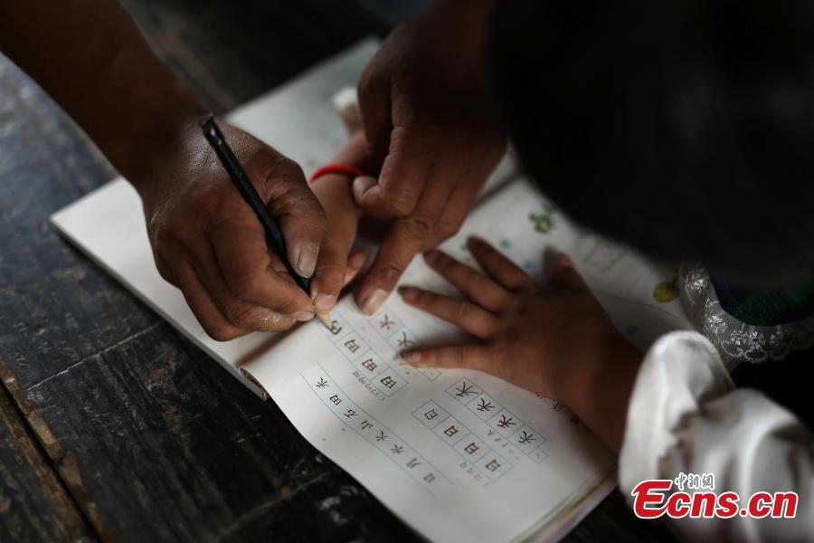Teacher Yang Changjun instructs Wang Fangying, a first grader, in writing at a school in Danggan Village, Paitiao Town, Guizhou Province, Sept. 7, 2018. Yang, 40, is the only teacher in the school that has one first grader and seven pre-school children from nearby villages. If not for the school, children would have to travel to a town more than 20 kilometers away to study. (Photo: China News Service/Huang Xiaohai)