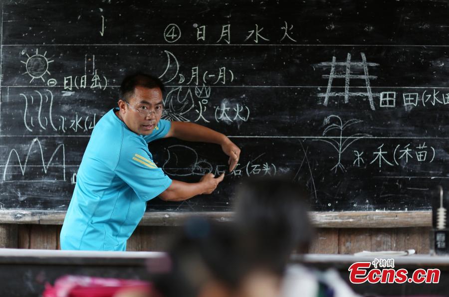 Yang Changjun teaches Chinese to Wang Fangying (C), a first grader, while his daughter, 6, also sits in the classroom at a school in Danggan Village, Paitiao Town, Guizhou Province, Sept. 7, 2018. Yang, 40, is the only teacher in the school that has one first grader and seven pre-school children from nearby villages. If not for the school, children would have to travel to a town more than 20 kilometers away to study. (Photo: China News Service/Huang Xiaohai)