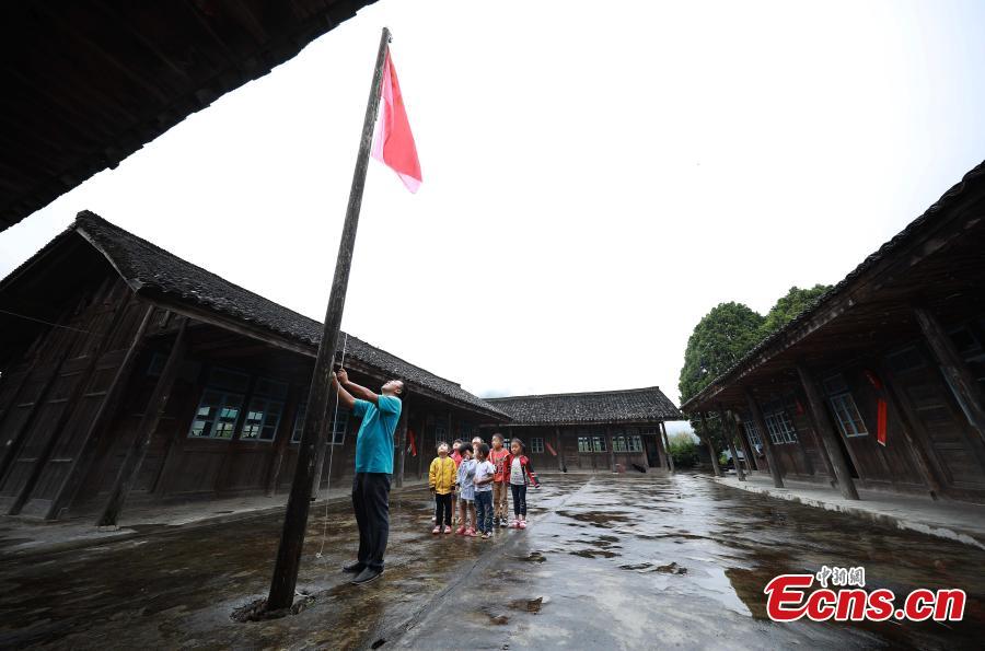 Yang Changjun leads children in the flag-raising ceremony at a school in Danggan Village, Paitiao Town, Guizhou Province, Sept. 7, 2018. Yang, 40, is the only teacher in the school that has one first grader and seven pre-school children from nearby villages. If not for the school, children would have to travel to a town more than 20 kilometers away to study. (Photo: China News Service/Huang Xiaohai)