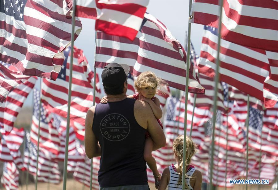 People walk among U.S. national flags erected to honor the victims of the September 11, 2001 attacks in New York, at the campus of Pepperdine University in Malibu, the United States, Sept. 10, 2018. (Photo/Xinhua)