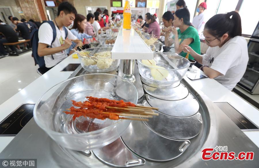 Photo taken on Sept. 12, 2018 shows a hot pot canteen at the Chang\'an Campus of Xi\'an University of Finance and Economics in Xi’an City, Northwest China’s Shaanxi Province. The canteen became popular among students for its rotary belt that delivers fresh, cheap ingredients and a variety of flavors. A student said spending 20 yuan can could get a good treat. (Photo/VCG)