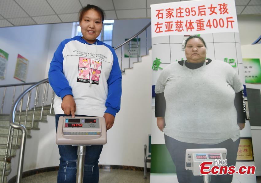 Zuo Yaci, 21, poses with a poster of her when she weighed up to 200 kilograms. She dropped out of school in Hebei Province because she was plus-size when just a second-year middle school student. Zuo began receiving treatment to lose weight at a hospital in Changchun, Jilin Province in September 2017, slashing her weight to 100 kilograms. She says she now feels more confident and optimistic about life. (Photo: China News Service/Zhang Yao)