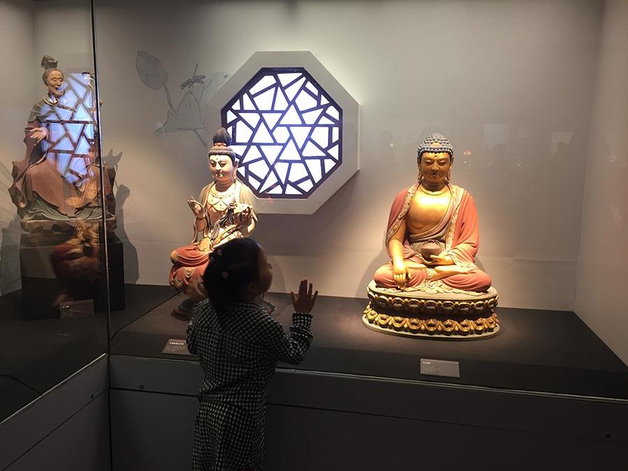 A child looks at colored sculpture shown at the exhibition. 
(Photo/China Daily)