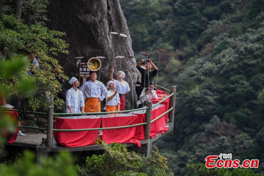 Chefs show stunt skills with kitchenware at a restaurant built on a cliff at Longquan Mountain in Zhejiang Province, Sept. 27, 2018. The restaurant 1,600 meters above sea level allows customers to dine on suspended plank roads while enjoying great views of the mountain. Longquan is the highest peak in the Yangtze River Delta. (Photo: China News Service/Yang Yong)