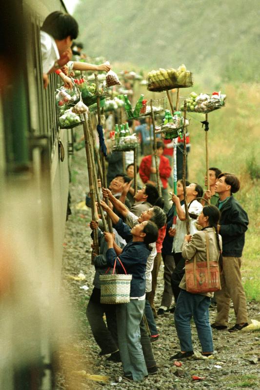 Villagers living near Qiangzilu Railway Station in Miyun district of Beijing, sell local specialties to passengers on a train from Beijing to Qinhuangdao, Hebei province, which stops at the station for five minutes, in October 1996. [ZHOU CHAORONG/FOR CHINA DAILY]