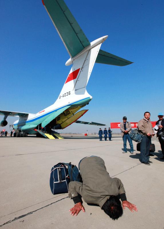 A 41-year-old Sinohydro Corp worker kisses the ground after getting off a plane in Beijing on March 4, 2011. The People\'s Liberation Army Air Force sent four planes to Libya to bring back Chinese nationals after a civil war broke out in the country. A total of 287 Chinese citizens took the planes back to China. It was the first time the PLA Air Force evacuated Chinese nationals from overseas. [SHEN LING/FOR CHINA DAILY]