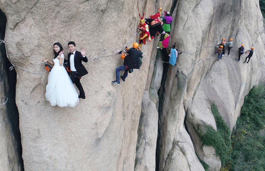 A couple poses for a wedding photo on a cliff at Chaya Mountain Scenic Zone in Zhumadian, Henan province, on Nov 11, 2017. [LU JIAN/FOR CHINA DAILY]