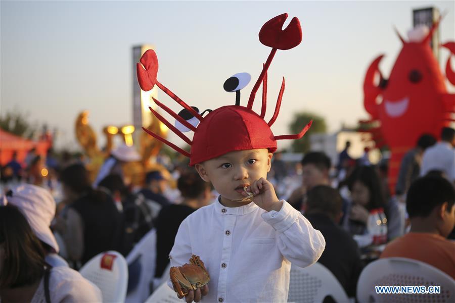 A child eats crab during a crab feast in Hongze District of Huai\'an, east China\'s Jiangsu Province, Oct. 2, 2018. Over 1,000 people participated in the activity here on Tuesday. (Xinhua/Wan Zhen)
