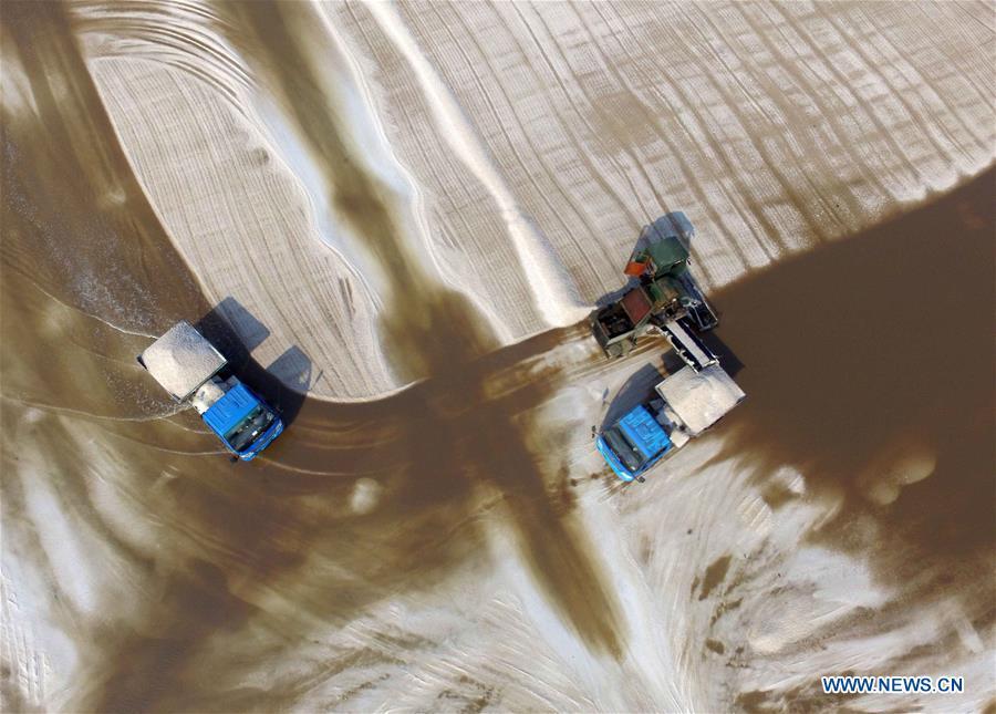 Workers manipulate machines to harvest salt at saltworks in Binzhou City, east China\'s Shandong Province, Oct. 4, 2018. The saltworks entered the harvest season recently. (Xinhua/Guo Zhihua)