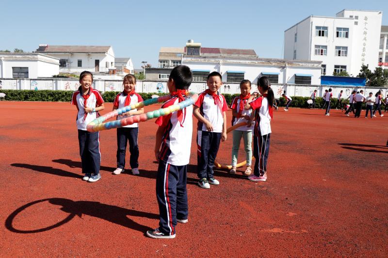 A boy from Xiaogang School, which includes nine grades, shows his hoop skills to his classmates during a break between classes on Sept. 27. (Photo/chinadaily.com.cn)