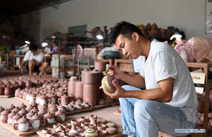 <?php echo strip_tags(addslashes(A staff member works on a Nixing pottery ware at a workshop in Qinzhou, south China's Guangxi Zhuang Autonomous Region, Oct. 9, 2018. The making of Nixing pottery is a well-preserved tradition in Qinzhou. In 2008, the techniques of making Nixing pottery were listed as one of China's state-level intangible cultural heritages. Currently, over 10,000 workers are engaged in the Nixing pottery industry in Qinzhou, producing more than 1,000 pottery varieties. (Xinhua/Lu Boan))) ?>