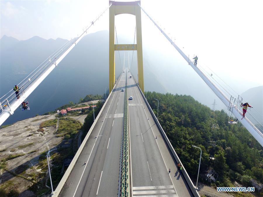 Staff members carry out cleaning and maintenance work on the main cables of the Sidu River Bridge in central China\'s Hubei Province, Oct. 10, 2018. The suspension bridge crosses the Sidu River valley near the boundaries of Yichang and Enshi in Hubei Province. The top point of the bridge is 650 meters above the bottom of the valley, a height comparable to a 200-storey skyscraper. (Xinhua/Zhu Wei)