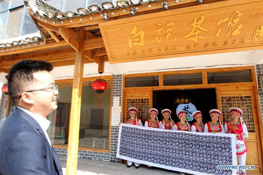 A guest is welcomed by women of Bai ethnic group at the door of a tea house at the Suoziqiu Village of Mahekou Township in Sangzhi County of Zhangjiajie City, central China\'s Hunan Province, Oct. 11, 2018. People of the Bai ethnic group here still follow the welcoming tradition of their immigrated ancestors to offer \