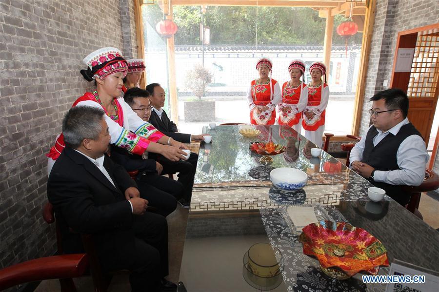 <?php echo strip_tags(addslashes(Women of Bai ethnic group serve tea to guests at a tea house at the Suoziqiu Village of Mahekou Township in Sangzhi County of Zhangjiajie City, central China's Hunan Province, Oct. 11, 2018. People of the Bai ethnic group here still follow the welcoming tradition of their immigrated ancestors to offer 