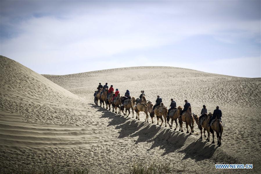 <?php echo strip_tags(addslashes(Tourists ride camels in Lop Nur People Village of Yuli County, northwest China's Xinjiang Uygur Autonomous Region, Oct. 16, 2018. The Lop Nur people depended basically on fishing for livelihood and developed a distinct culture based on their special lifestyle. Located in Tarim basin, Yuli is known for its natural scenery and ethnic culture and keeps attracting numerous tourists from at home and abroad. From Oct. 1 to 16, 2018, Yuli County has received more than 230,000 visitors, with a year-on-year increase of 31.46 percent. (Xinhua/Zhao Ge))) ?>