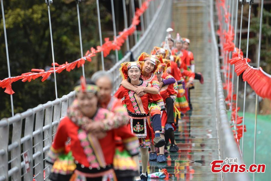 <?php echo strip_tags(addslashes(Women carrying their mothers-in-law on their back compete in a race on the 140-meter-long glass bridge in Jiulong River National Forest Park in Hunan Province, Oct. 16, 2018, ahead of the Double Nine Festival. Women from the She and Yao ethnic groups participated the competition. The 9th day of the 9th lunar month is the traditional Chongyang Festival, or Double Nine Festival, which falls on Oct. 17 this year. (Photo: China News Service/Yang Huafeng))) ?>