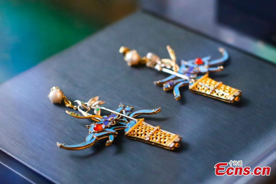 Artist Ma Jingji shows 30 pieces of Diancui works he has collected or created at an exhibition in Chongqing, Oct. 22, 2018. Diancui, or dotting with kingfishers, is a painstakingly time-consuming and precise practice of inlaying iridescent kingfisher feathers into accessories for the rich and noble. Craftsmen apply the shimmering feathers to jewelry, hairpins, bracelets, brooches, fans, and landscape panels. Instead of kingfisher feathers, goose feathers and ribbons are used nowadays to make art creations with diancui skills.(Photo: China News Service/Zhong Xin)