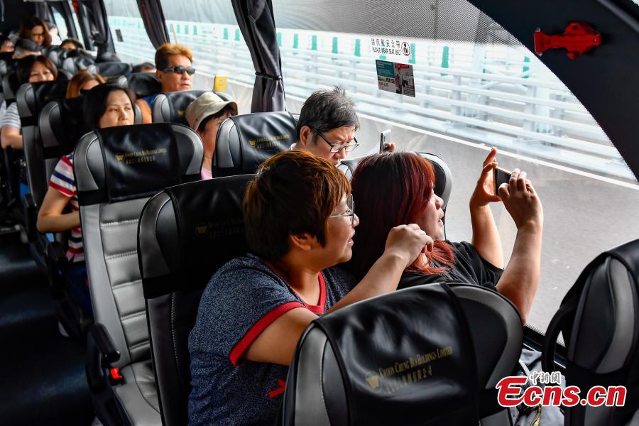 Passengers inside a coach take photos of the Zhuhai-Hong Kong-Macao Bridge. (Photo: China News Service/ Chen Jimin)