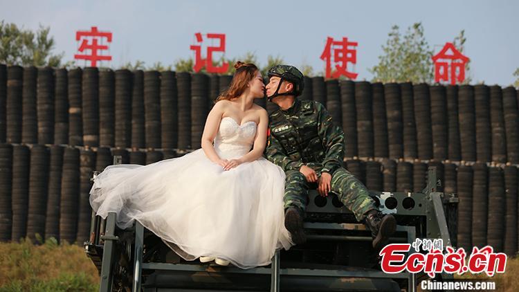 An armed police squad head in Yantai City, East China’s Shandong Province and his wife took special wedding photos at a barrack amid cheers and support of other members of the paramilitary police unit. (Photo: China News Service/Yang Lei)