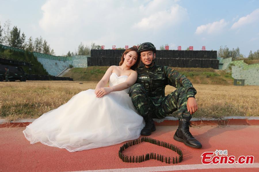 An armed police squad head in Yantai City, East China’s Shandong Province and his wife took special wedding photos at a barrack amid cheers and support of other members of the paramilitary police unit. (Photo: China News Service/Yang Lei)
