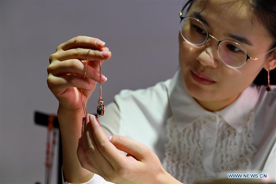 Chen Qin shows a wood carving ornament designed by herself in Putian, southeast China\'s Fujian Province, Oct. 23, 2018. Lin Jianjun, who learnt wood carving at the age of 16, has studied the making skill of this traditional artwork for more than 20 years. In 2014, Lin got married with Chen Qin. The wife was influenced by her husband and got interested in wood carving. She developed the wood carving by combining a traditional skill to make wood carving inlaid with gold and silver. The couple meanwhile try to promote the Putian wood carving by giving lessons, instructing apprentices and displaying their works to the public. In 2018, Lin was appointed as the inheritor of the wood carving skill, a provincial-level intangible cultural heritage.(Xinhua/Zhang Guojun)