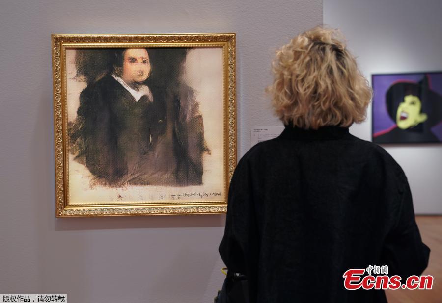 A woman looks at a work of art created by an algorithm by French collective named OBVIOUS which produces art using artificial intelligence, titled \