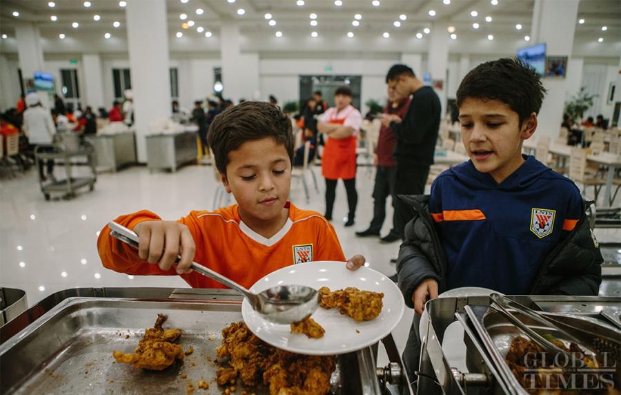 Young soccer players fill their plates for dinner at the school\'s mess hall. (Photo: Li Hao/GT)