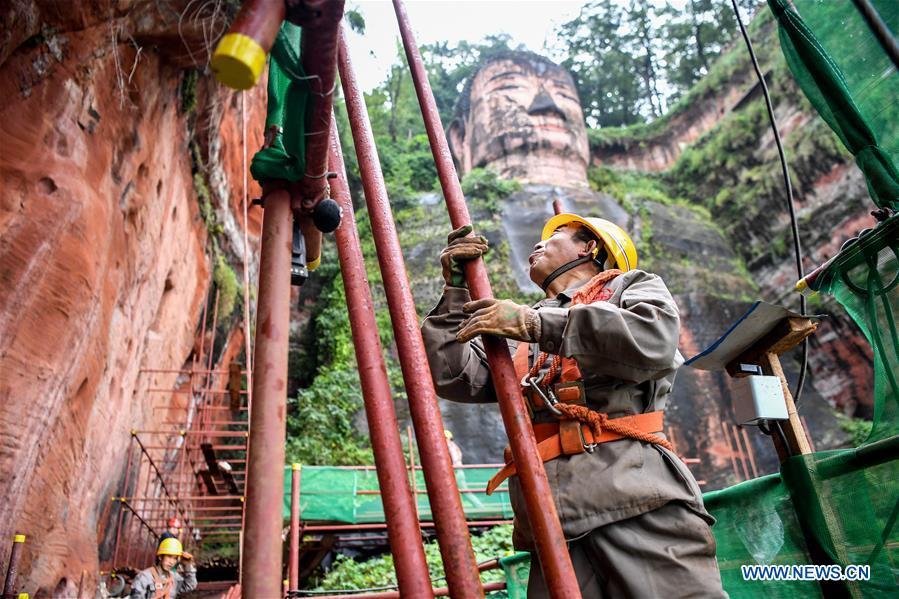 Workers install scaffolds for the examination work of the Leshan Giant Buddha in Leshan City, southwest China\'s Sichuan Province, Oct. 19, 2018. The examination of Leshan Giant Buddha started on Oct. 8 to collect data for better restoration. (Xinhua/Zhang Chaoqun)