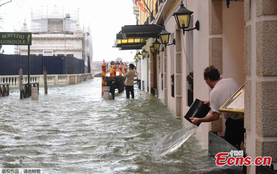 A man empties a bucket of water on a flooded street during a high-water alert in Venice on October 29, 2018. - The flooding, caused by a convergence of high tides and a strong Sirocco wind, reached 150 centimetres on October 29. (Photo/Agencies)