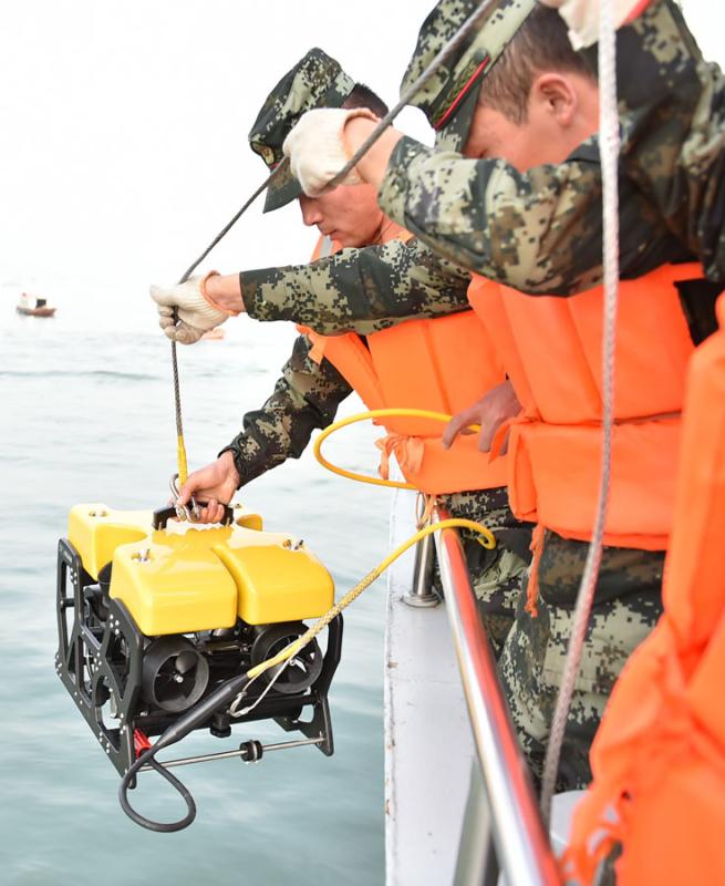 Armed police officers use an underwater robot to search for victims of the crash on Sunday. (Photo by Zhao Hui/For China Daily)
 
As of Monday morning, at least 70 rescue boats had arrived at the scene, including three floating cranes with total capacity of 125 metric tons. Civilian rescue teams are also contributing and some of the 15 divers on scene are from teams such as Blue Sky Rescue Team and Zhejiang Rescue Team of Ramunion, according to the ministry.

Video taken by the data recorder of a car behind the bus showed that it swerved suddenly onto the wrong side of the road on the Second Yangtze River Bridge, more than 50 meters above the water.

The bus ran into an oncoming car before breaking through the guardrail and plunging into the river. The incident took no more than 10 seconds. There was no sign of braking by the bus, video published by Chengdu Economic Daily shows.

The female driver of the oncoming car was not seriously injured, reports said.