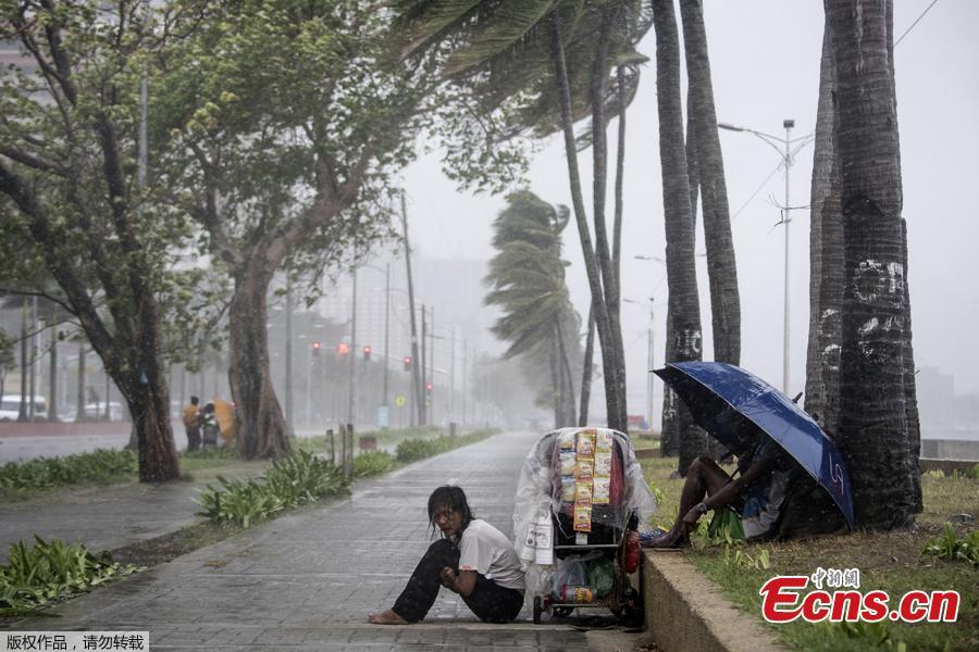 A streetside vendor shivers in the rain as weather patterns from Typhoon Yutu affect Manila Bay on Oct. 30, 2018. Typhoon Yutu slammed into the Philippines on Tuesday with fierce winds that sheared off roofs and snapped trees in half, after thousands were evacuated ahead of the powerful storm\'s arrival. (Photo/Agencies)