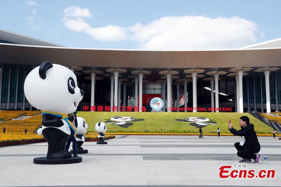 A volunteer for the upcoming China International Import Expo (CIIE) poses for a photo with the mascot \