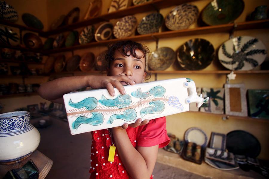 A girl shows an artwork during the eighth annual Tunis Pottery and Handcrafts Festival in Tunis village, Fayoum province, south of Cairo, capital of Egypt, on Nov. 1, 2018. Crowds of local and foreign visitors have been walking around the little pottery and art shops of Tunis village during the eighth annual Tunis Pottery and Handcrafts Festival. The three-day festival, which kicked off on Nov. 1, showcases unique artworks of pottery and several other handcrafts including wood and granite carving, basket making, handmade carpets, needlework, clay objects and hammered copper. (Xinhua/Ahmed Gomaa)