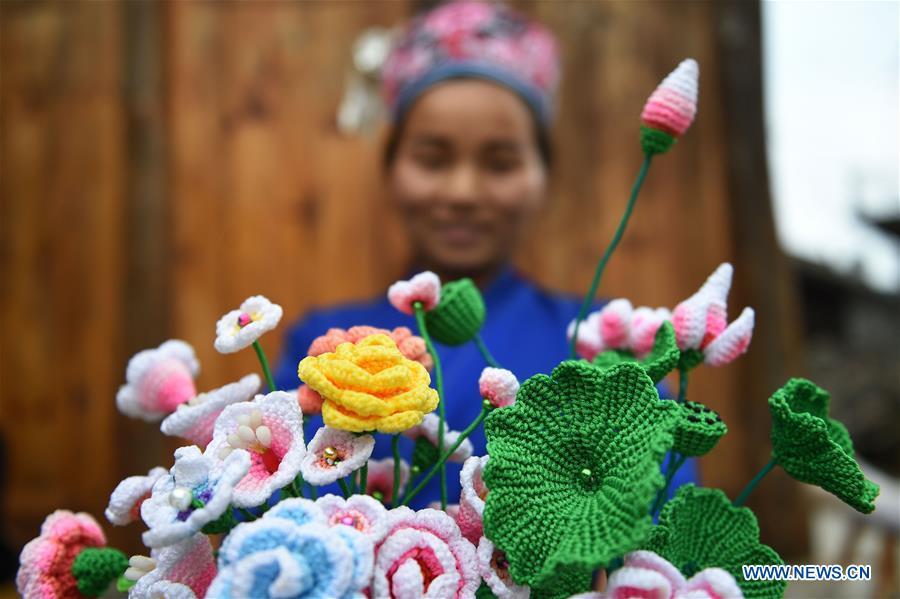 Yang Xinghe shows decorations made by wool thread at Xinjiang Village in Taijiang County of Qiandongnan Miao and Dong Autonomous Prefecture, southwest China\'s Guizhou Province, on Nov. 4, 2018. Born with hearing loss, Yang Xinghe, 28, is a female of the Miao ethnic group, who are engaged in Miao embroidery at the village. She learned embroidery from her mother when she was only a child, and has been a locally well-known master now. (Xinhua/Liu Kaifu)