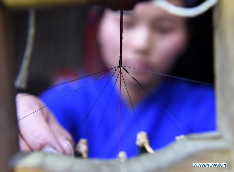 Yang Xinghe weaves ribbon at Xinjiang Village in Taijiang County of Qiandongnan Miao and Dong Autonomous Prefecture, southwest China\'s Guizhou Province, on Nov. 4, 2018. Born with hearing loss, Yang Xinghe, 28, is a female of the Miao ethnic group, who are engaged in Miao embroidery at the village. She learned embroidery from her mother when she was only a child, and has been a locally well-known master now. (Xinhua/Liu Kaifu)
