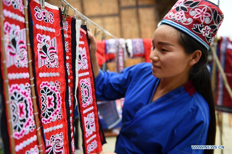 Yang Xinghe shows embroidered decorations for Miao costumes at Xinjiang Village in Taijiang County of Qiandongnan Miao and Dong Autonomous Prefecture, southwest China\'s Guizhou Province, on Nov. 4, 2018. Born with hearing loss, Yang Xinghe, 28, is a female of the Miao ethnic group, who are engaged in Miao embroidery at the village. She learned embroidery from her mother when she was only a child, and has been a locally well-known master now. (Xinhua/Liu Kaifu)