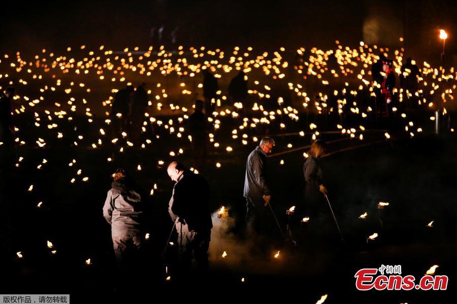 <?php echo strip_tags(addslashes(Volunteers light torches that are part of the installation 