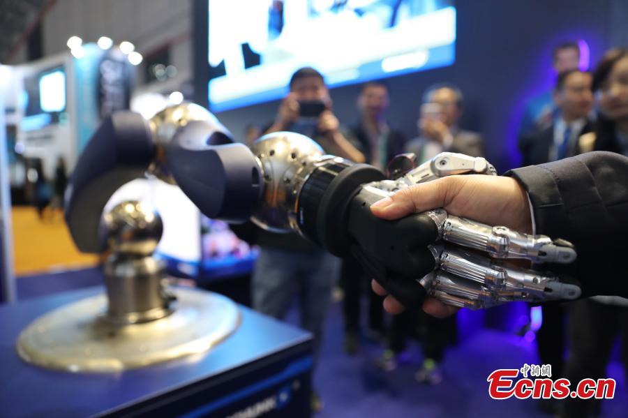 Visitors are attracted by a robotic hand shown at the first China International Import Expo (CIIE) in Shanghai, east China, Nov. 7 2018. The SCHUNK SVH 5-finger gripping hand is amazingly similar to the human model in terms of size, shape and agility. Nine drives enable the robotic hand to carry out gripping operations like holding a needle. (Photo: China News Service/Zhang Hengwei)
